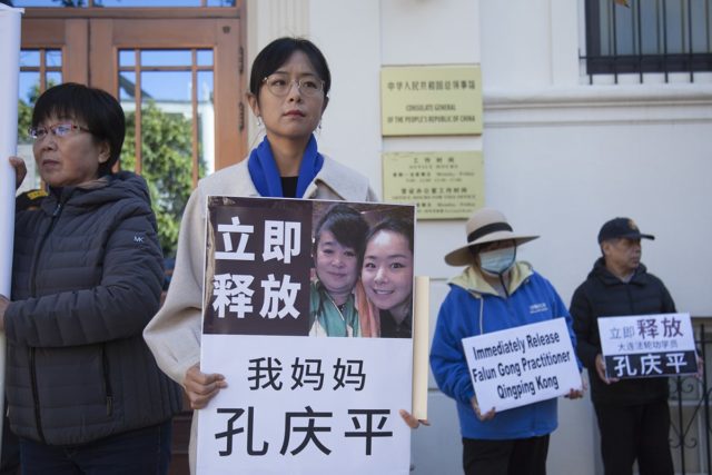 La Sra. Liu Zhitong sostiene una fotografía de su madre. El cartel dice: "Liberen inmediatamente a mi madre Kong Qingping". (Minghui.org)